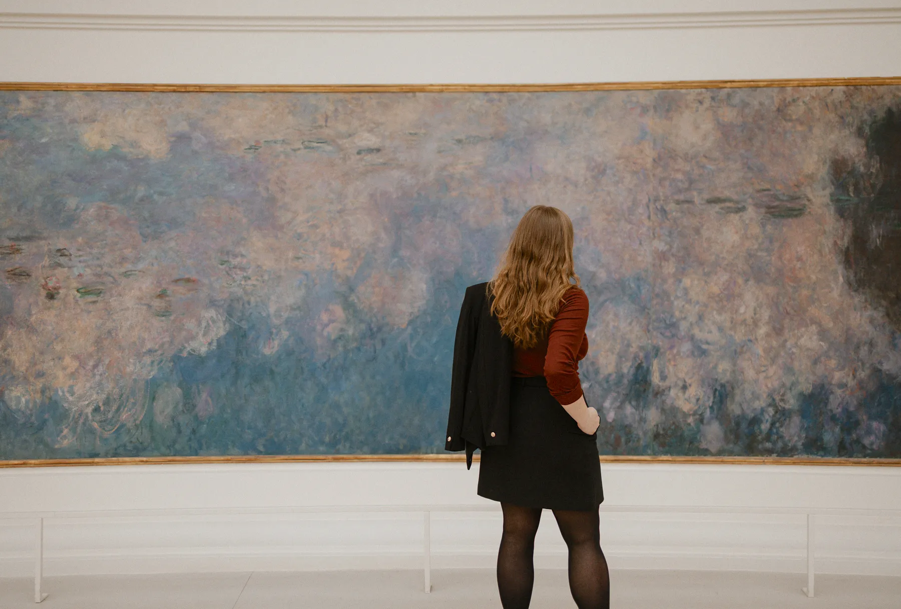 Woman observing Monet&rsquo;s Water Lilies painting, illustrating mindful art engagement and focused viewing
